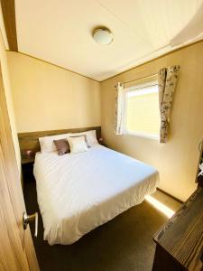 Un pequeño dormitorio con una cama blanca y una ventana en Dizzard 23, en Bridgerule