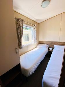 two beds in a small room with a window at Dizzard 23 in Bridgerule