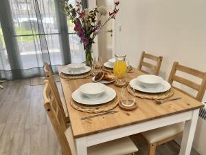 una mesa de madera con platos y vasos y un jarrón de flores en The Coorie en Bargrennan