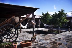 a stone courtyard with a wooden cart and potted plants at Agroturismo La Gayria in Tiscamanita