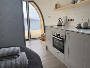 a kitchen with a counter with a stove top oven at Sunset Cabin- glass frontage luxury couples cabin. in Shieldaig