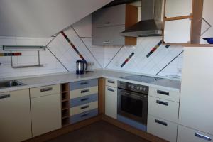 cocina con armarios blancos y fogones en Ferienwohnung Rosengarten, en Öhringen