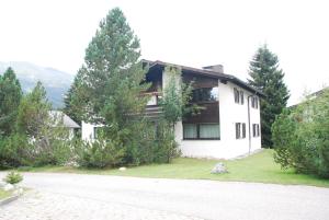 une maison blanche avec des arbres au bord d'une route dans l'établissement Lodola 298 2 Hk , Wohnung 2, à Lenzerheide