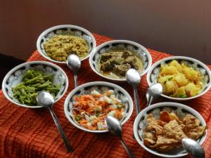 a group of bowls of food on a table with spoons at Minara Guest House in Mirissa