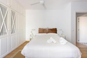a white bedroom with a white bed with towels on it at Stay U-nique apartment Venezuela in Málaga