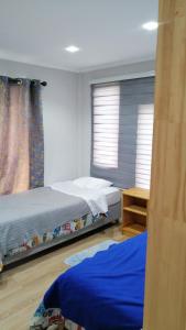 a bedroom with two beds and a table and two windows at Alojamiento Freire - Caviahue in Freire
