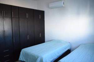 a bedroom with two beds and black cabinets at 3 HABITACIONES, CERCA DE LA PLAYA, Cantera Residencial in San Carlos