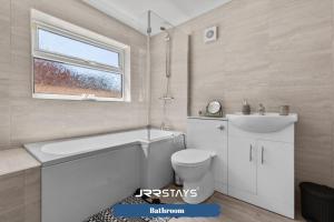 a bathroom with a tub and a toilet and a sink at Nuneaton - Ideal 3 Bedroom, Wi-fi Parking, Sleeps 6 - JRR Stays in Stockingford +17 photos