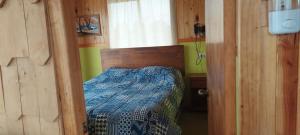ein Schlafzimmer mit einem Bett in einem Holzzimmer in der Unterkunft Cabañas y Camping Los Copihues in Ancud