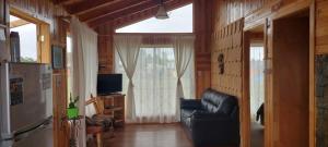 uma sala de estar com uma cadeira de couro preta e uma janela em Cabañas y Camping Los Copihues em Ancud