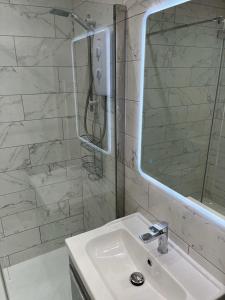 a white bathroom with a sink and a mirror at Port Pour Deux in Portrush