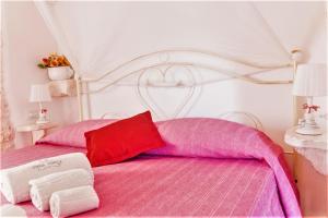 een slaapkamer met een wit en roze bed en 2 handdoeken bij B&B Trulli Donna Isabella in Locorotondo