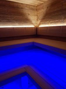 a swimming pool with blue lights in a wooden room at Penzión Šafran in Stratená