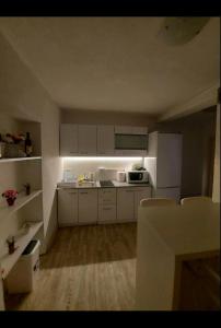una pequeña cocina con armarios blancos y una mesa en Apartment Center 23, en Podgorica