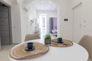 un tavolo bianco con due tazze e una pianta in vaso di MY BRILLIANT HOME WITH JACUZZI 2 STEPS FROM St TOLEDO a Napoli