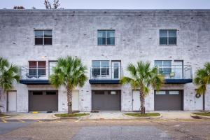 a building with three garage doors and palm trees at Walkable Downtown Apt with Game Room! in Mobile