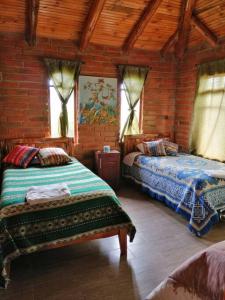 1 Schlafzimmer mit 2 Betten in einem Zimmer mit Fenstern in der Unterkunft Cabaña Puñushiki kalera Lodge 