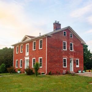 una vieja casa de ladrillo rojo con un patio de hierba en Farmhouse Broad Brook: Comfort & Charm., en East Windsor