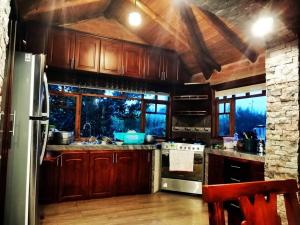 La cuisine est équipée de placards en bois et d'un four avec plaques de cuisson. dans l'établissement Cabaña Puñushiki kalera Lodge, 