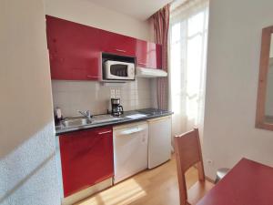 una piccola cucina con armadi rossi e lavandino di Val de Jade, la Cardabelle, T2, centre Luchon, wifi, casier à ski, 4 personnes a Luchon