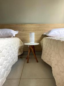 um quarto com duas camas e uma pequena mesa entre elas em Dois quartos com varanda - super espaçoso em Barra do Piraí