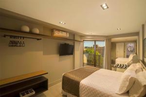 a bedroom with a bed and a television and a balcony at Infinity at the Sea by Matka in João Pessoa