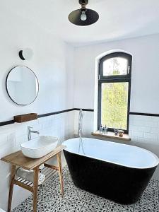 baño con bañera, lavabo y ventana en Ublik Stacja, en Ublik