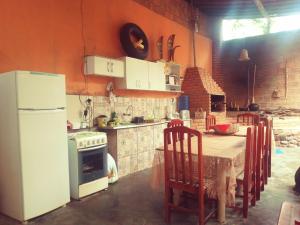 a kitchen with a table and a white refrigerator at Sítio com suítes e áreas de Lazer in Palmeiras