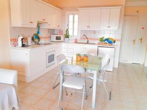 a kitchen with white cabinets and a table and chairs at Lovely Apartment in Tenerife South in Chayofa