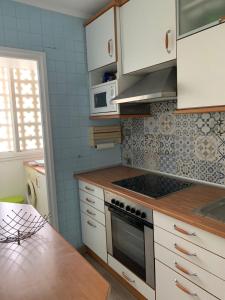 a kitchen with white cabinets and a stove top oven at Encantador apartamento en Dénia primera línea. in Denia