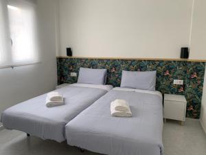 two beds in a bedroom with towels on them at Apartamento junto a Estación Ave · 3 dormitorios in Granada