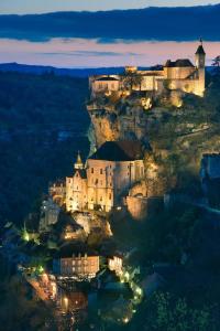 um castelo no topo de uma montanha à noite em Camping les Campagnes em Rocamadour
