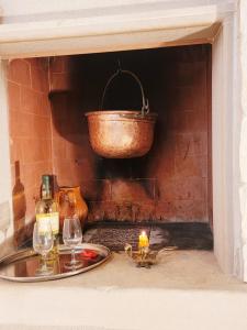 una olla de cobre en una chimenea con un plato y vasos en GIOVINAZZO HISTORIC APULIA old town stone house with private patio, en Giovinazzo