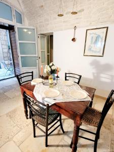 ein Esszimmer mit einem Tisch mit 4 Stühlen, einem Tisch und einem Chairsktop in der Unterkunft GIOVINAZZO HISTORIC APULIA old town stone house with private patio in Giovinazzo