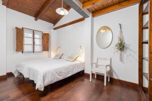 1 dormitorio con cama, espejo y silla en Casa Camino del Dobra, Centro de Cantabria, en Viérnoles