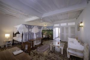 a living room with a bed, chair, and table in it at Sandies Tropical Village in Malindi