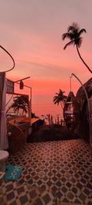 um pôr-do-sol sobre uma praia com palmeiras e o oceano em Obrigado by Craftels em Cabo de Rama