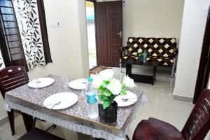 una mesa de comedor con platos blancos y flores. en Kumbakonam Inn Hotels - Kumbakonam Inn Stay en Kumbakonam