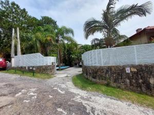 una cerca blanca sentada junto a una pared de piedra en Loft Barra da Fortaleza com Piscina, en Florianópolis