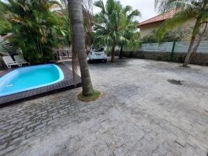 una piscina junto a una casa con una palmera en Loft Barra da Fortaleza com Piscina, en Florianópolis