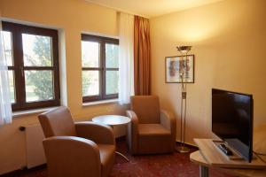 a hotel room with chairs and a tv and windows at Hotel Luitpold am See in Prien am Chiemsee