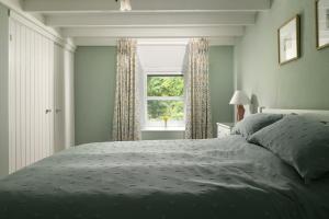 a bedroom with a large bed and a window at Swan Cottage in Llangelynin