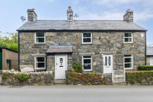 an old stone house with white doors and windows at Swan Cottage in Llangelynin