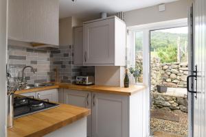 Una cocina con gabinetes blancos y una ventana. en Tan y Celyn, en Llangelynin