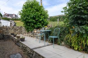 a patio with a table and chairs in a garden at Tan y Celyn in Llangelynin