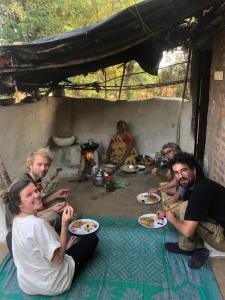 un gruppo di persone seduti sul pavimento con piatti di cibo di Maji Homestay Khajuraho a Khajurāho