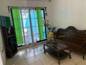 a living room with a couch and green curtains at Casa 2 a 5 min del Irtra in Retalhuleu