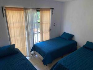 1 Schlafzimmer mit 2 Einzelbetten und einem Fenster in der Unterkunft Casa 2 a 5 min del Irtra in Retalhuleu