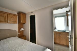 レ・マトゥにあるMobil'home Les Pommes de Pin aux Mathes La Palmyre terrain privéのベッドルーム1室(ベッド1台付)、スライド式ガラスドアが備わります。