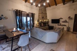 a living room with a fireplace and a bed and a table at Ονειροπαγιδα in Karpenisi